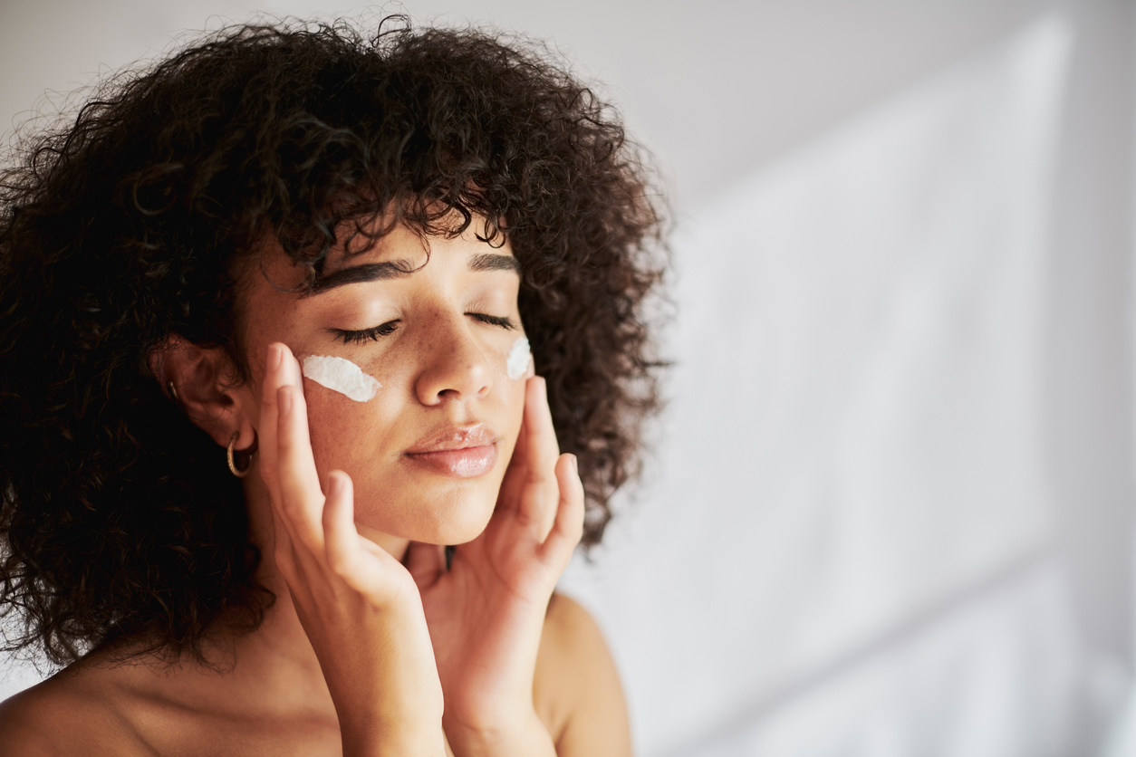 Cream, moisturizer and facial black woman in skincare, beauty or cosmetics promotion on white wall background. Face, calm and gen z people or model lotion, essential oil or moisturizer for skin care